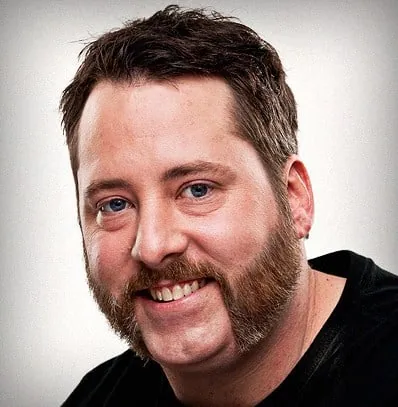 Smiling man with friendly mutton chops connected by a mustache