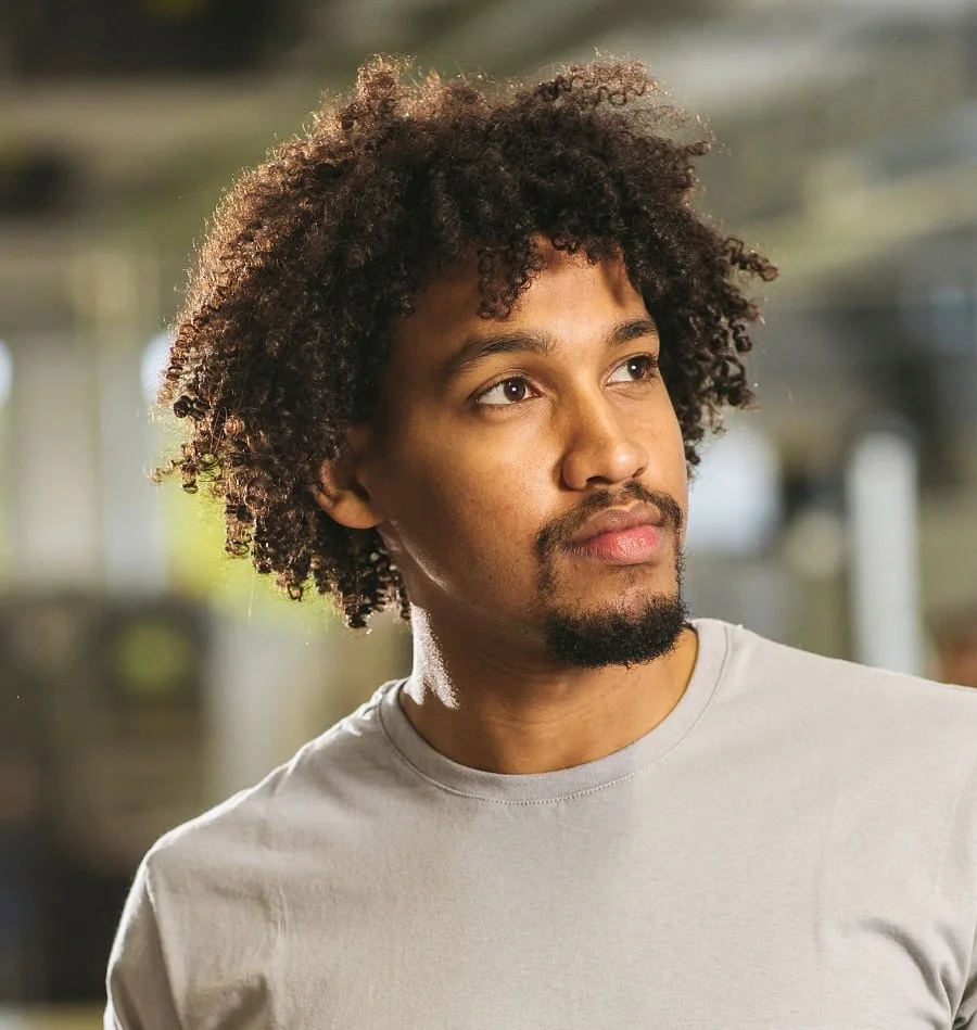 Portrait of curly haired bearded young male hipster stock photo