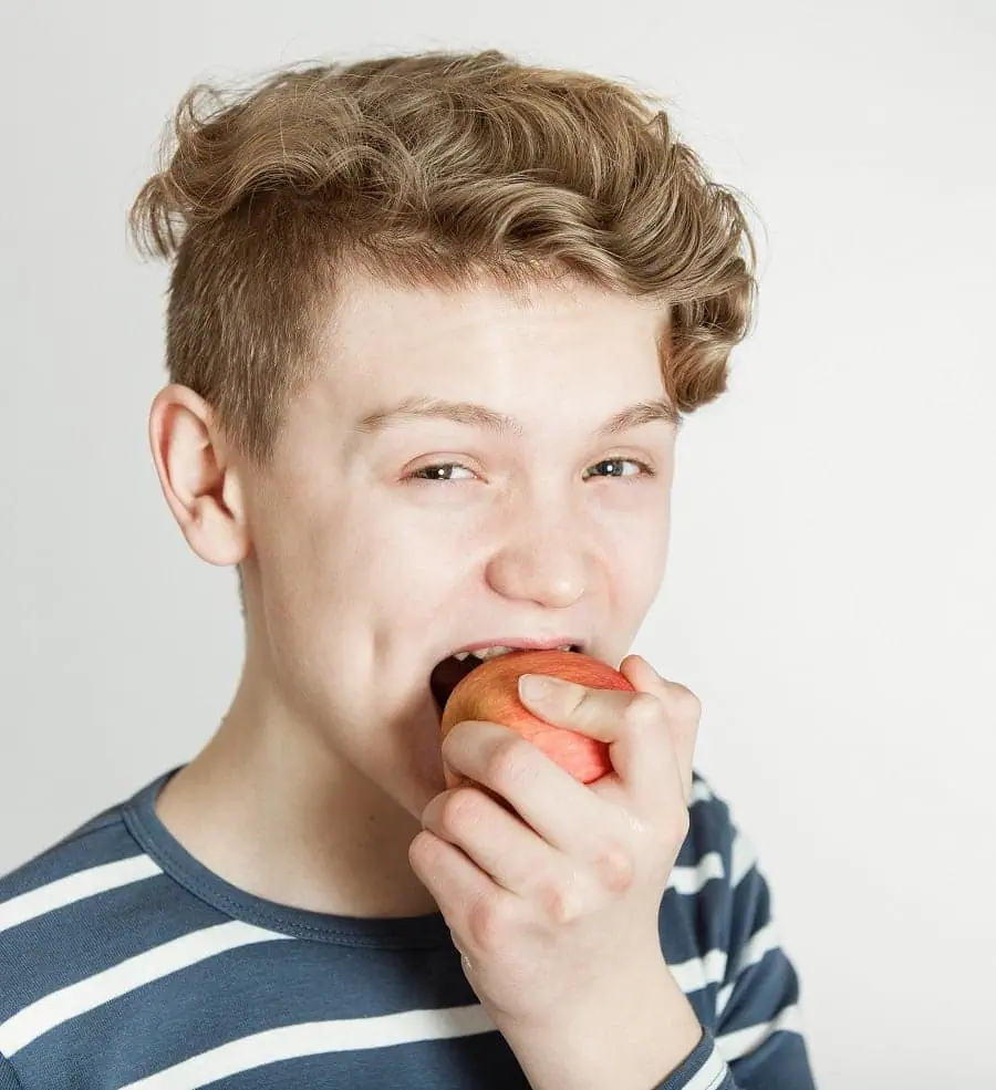 Teen boy biting into a red apple as part of a healthy diet