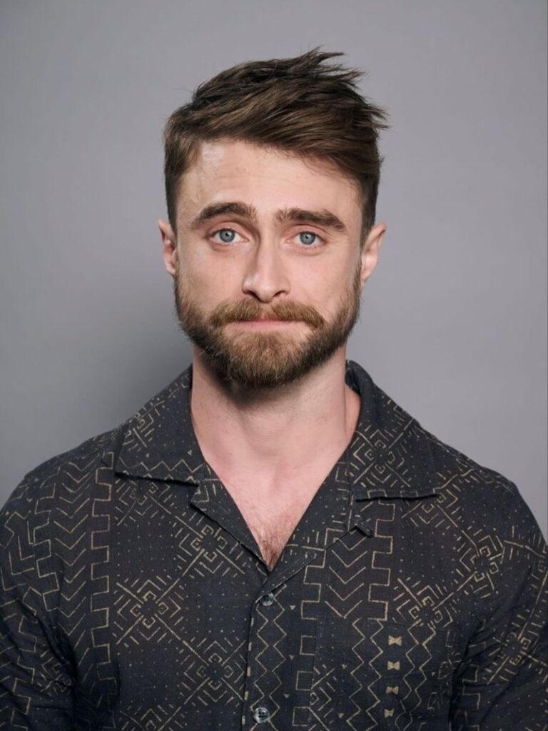 Daniel Radcliffe with a prominent mustache and heavy stubble